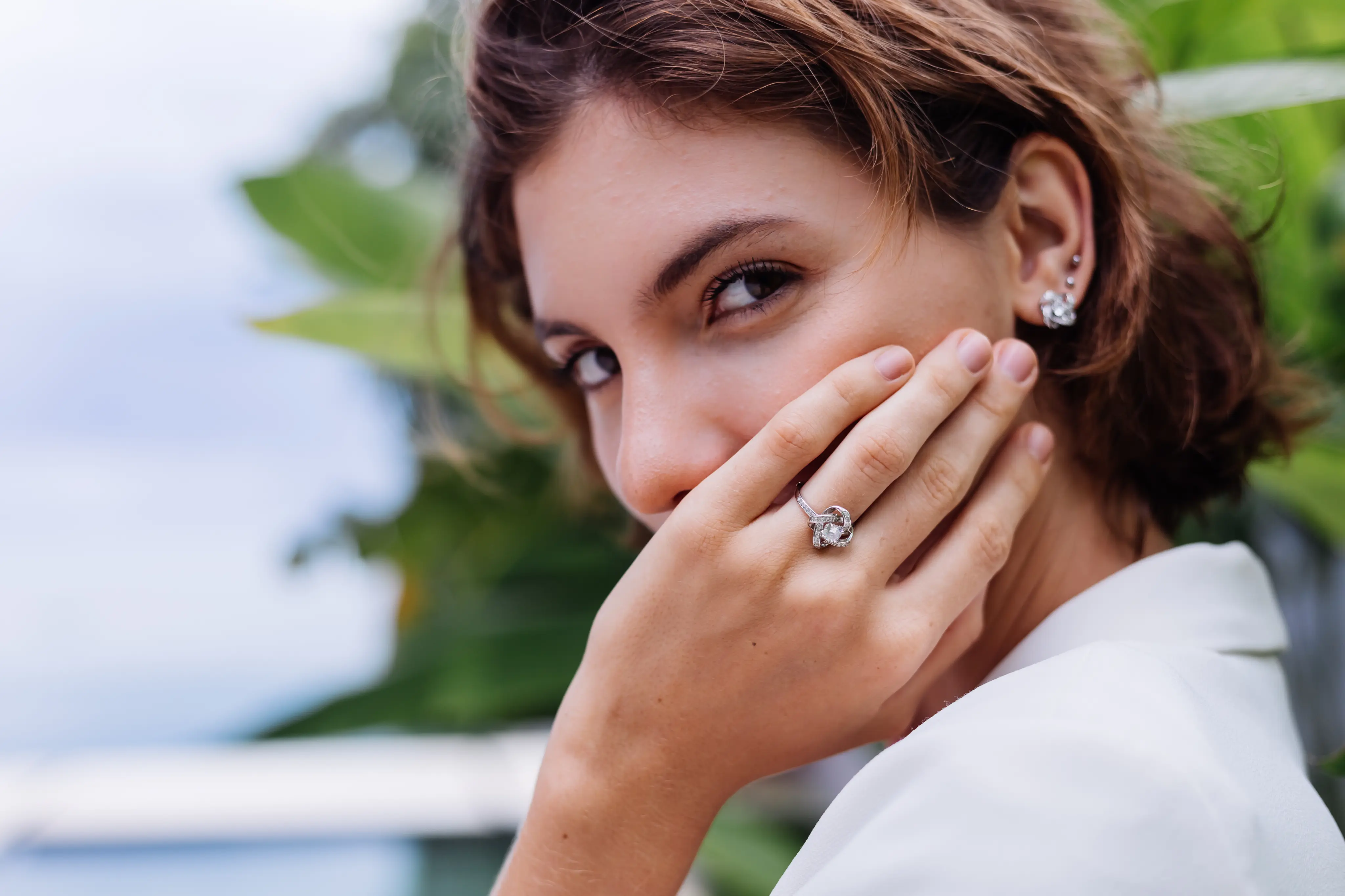 Young woman wearing a diamond ring and earrings with a thoughtful expression